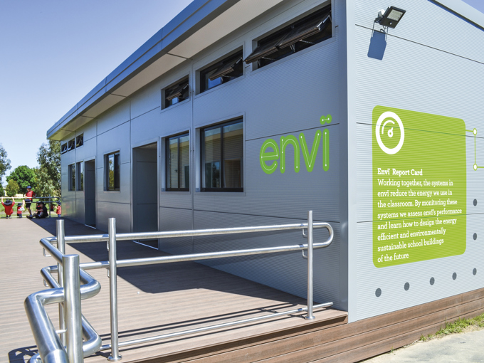 Bâtiment scolaire moderne de conception modulaire, doté de petites fenêtres ouvertes sur le mur extérieur et d'une rampe d'accès pour les personnes à mobilité réduite.